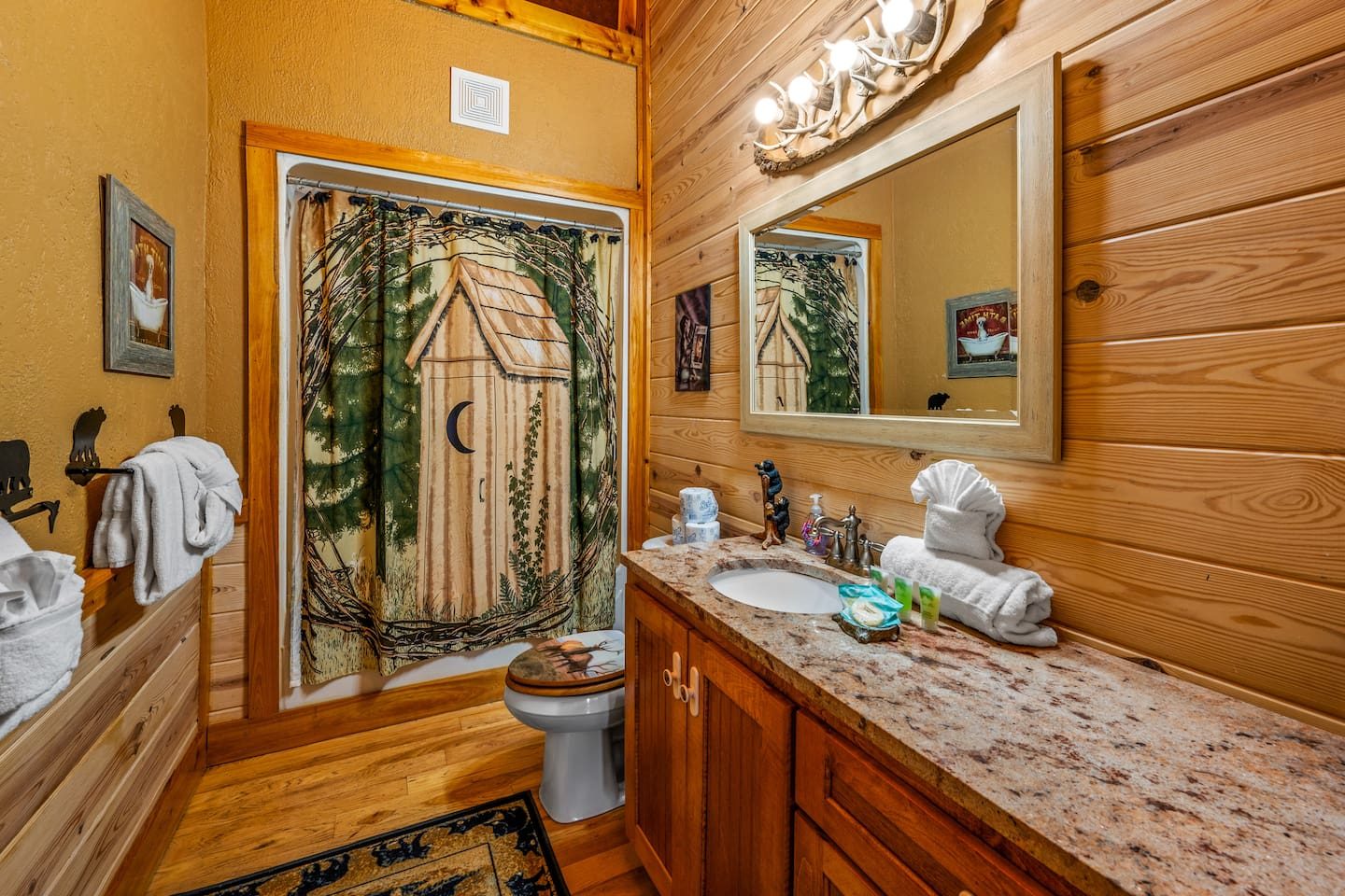 A playful outhouse shower curtain, rustic wood and a long granite vanity. Cabin charm in every detail, and plenty of room to get ready together.