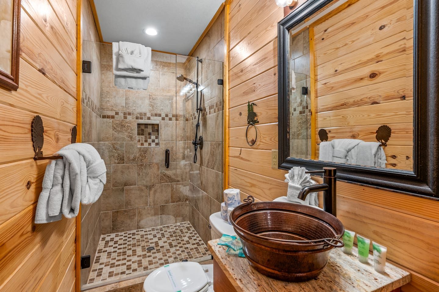 A hammered copper sink, warm pine walls and a tiled walk-in shower. A bath with real cabin character, and fresh towels waiting.