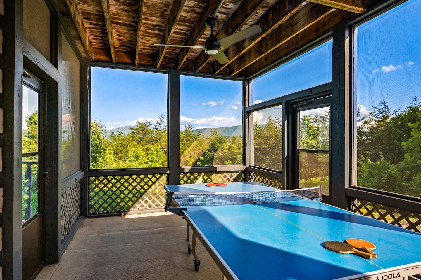 A screened-in porch with a ping-pong table and treetop views. Paddle, rally and cheer with a mountain breeze rolling through.