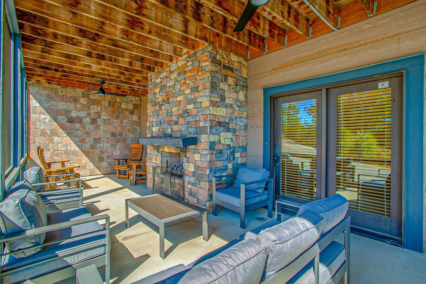 Lower-level lounging with a stone fireplace and deep patio seating. Gather here on cool evenings for warmth and conversation.