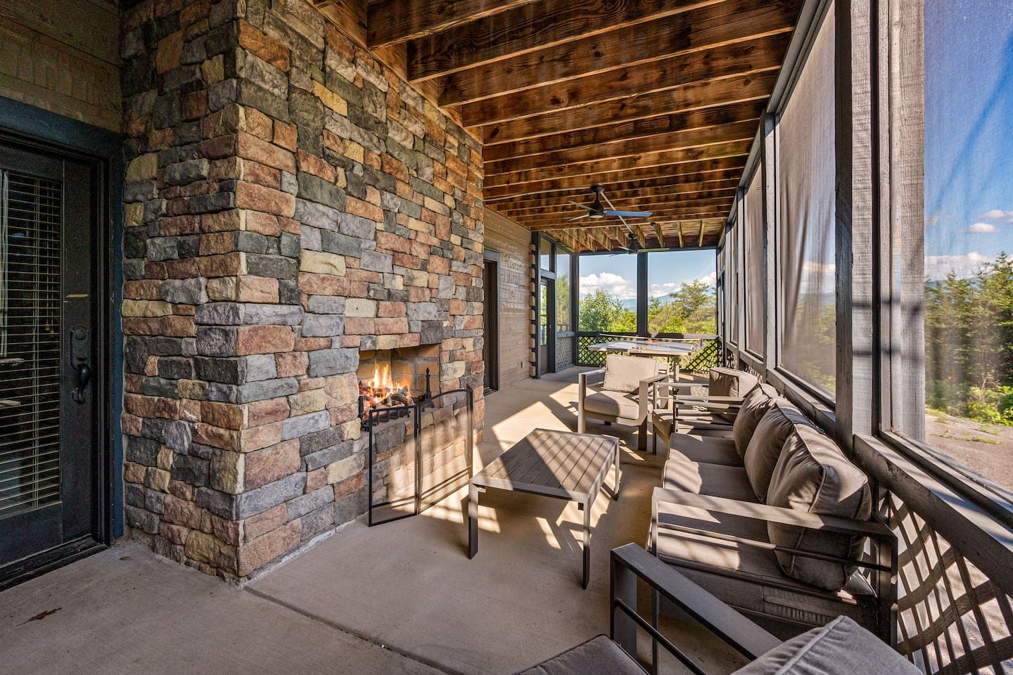 A screened porch with a stone fireplace, soft seating and a breeze through the trees. Bug-free evenings feel like pure magic.